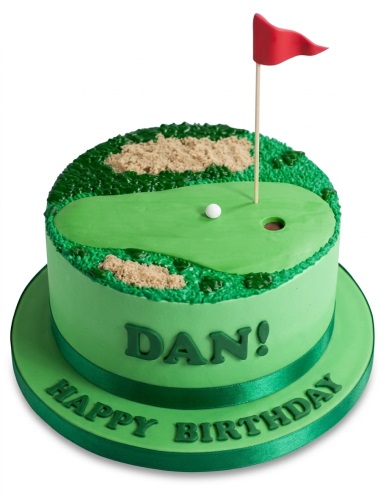 Round green golf course birthday cake with sand bunkers, a white golf ball, and a red flag.