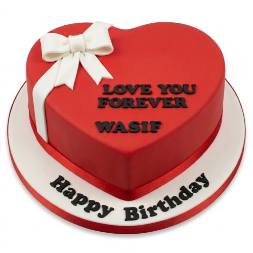 Red heart-shaped birthday cake with a white fondant bow and custom message.
