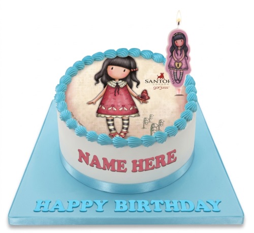 Round white birthday cake with an edible Gorjuss doll image and blue shell piping.