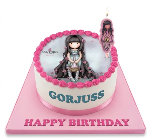 Round white cake with Gorjuss doll edible image, pink piping, and "GORJUSS" text on a pink board.