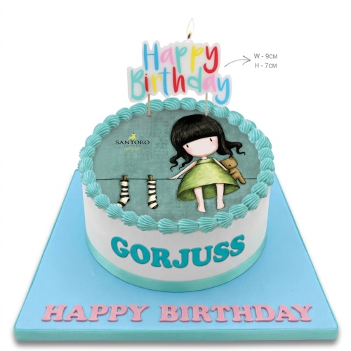 Round white birthday cake with a Gorjuss doll edible image and "Happy Birthday" topper.