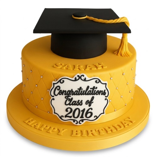 Yellow round cake with black graduation cap, gold tassel, quilted side with pearls, and a white plaque.