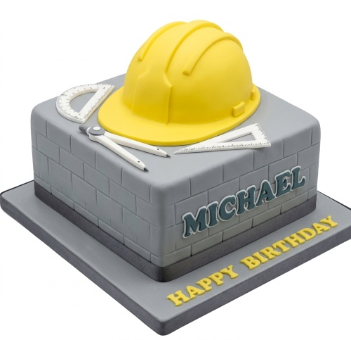 Square grey cake with yellow hard hat, drafting tools, and brick pattern.