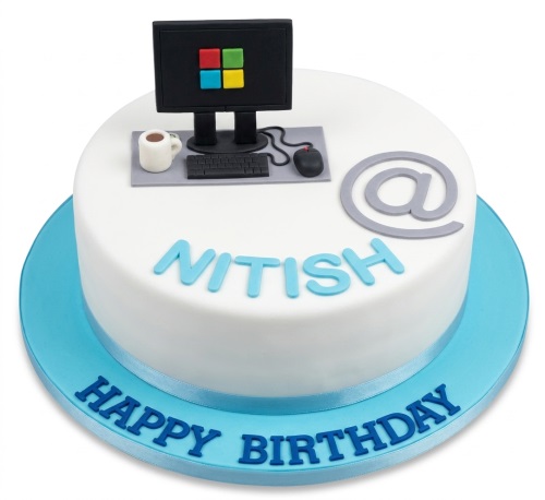 Round white birthday cake with edible computer monitor, keyboard, mouse, coffee mug, and an "@" symbol.