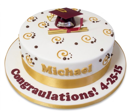 Round white graduation cake with maroon cap, gold diploma, gold swirls, and a gold ribbon.