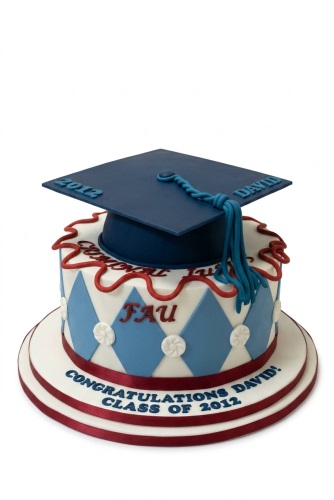 Round graduation cake with a blue cap topper, blue and white diamond pattern, and red accents. Features customisable year and name.