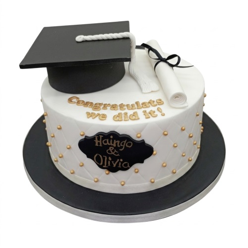 White graduation cake with black mortarboard, diploma, gold pearls, and custom message.
