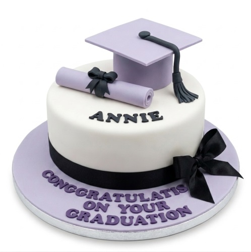 White and lavender graduation cake with black cap, scroll, and custom message.
