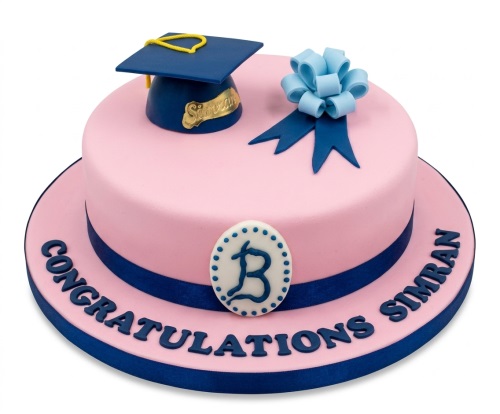 Pink graduation cake with blue cap, bow, and 'Congratulations' message