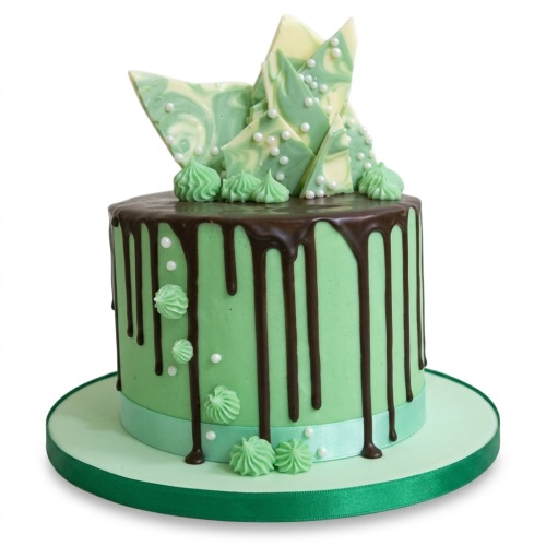 Round mint green drip cake with chocolate, marbled chocolate shards, and white sprinkles.