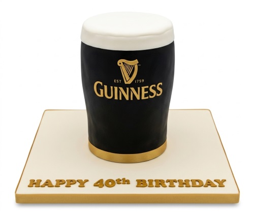 3D Guinness pint shaped birthday cake with white foam top and gold logo, on a white board.