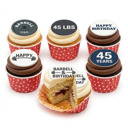 Six gym-themed cupcakes with barbell and weight designs, including 'Happy Birthday' and custom age toppers in red polka dot cases. One cupcake is cut open to show jam filling.