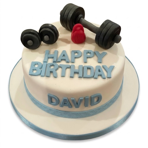Round white birthday cake with edible grey dumbbells, red kettlebell, and blue 'Happy Birthday' text.