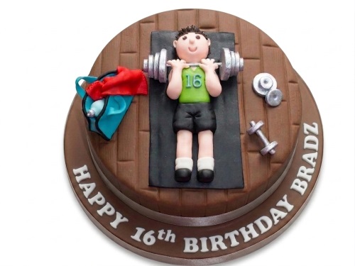 Round two-tier gym themed birthday cake with a fondant figure lifting weights, dumbbells, and a gym bag.