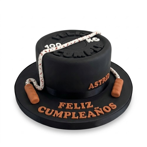 Round black gym theme birthday cake with a weight plate design and a white skipping rope.