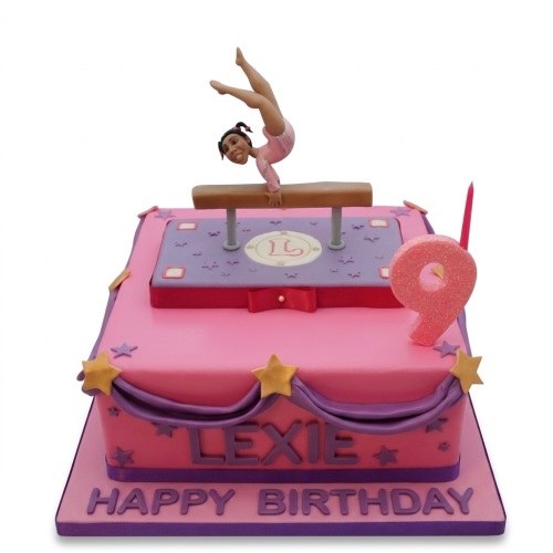Two-tier pink and purple gymnastics birthday cake with gymnast figure and custom age topper.