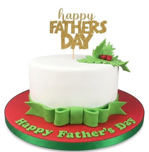 White round cake with gold Happy Father's Day topper, green ribbon, holly leaves, and red berries on a red board.