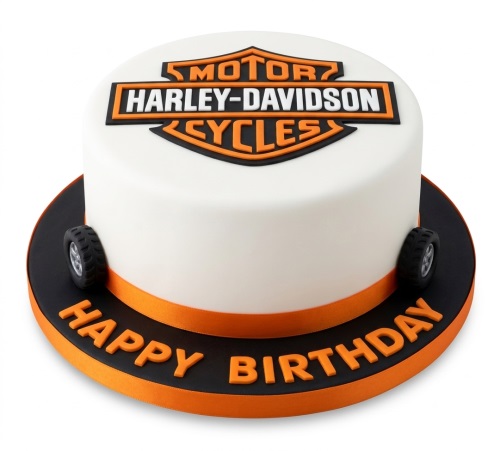 White round Harley Davidson birthday cake with orange logo, wheels, and "Happy Birthday" text.
