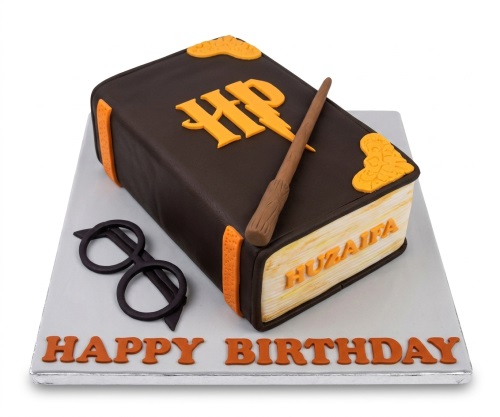Dark brown book-shaped Harry Potter birthday cake with orange HP logo, wand, and black glasses.
