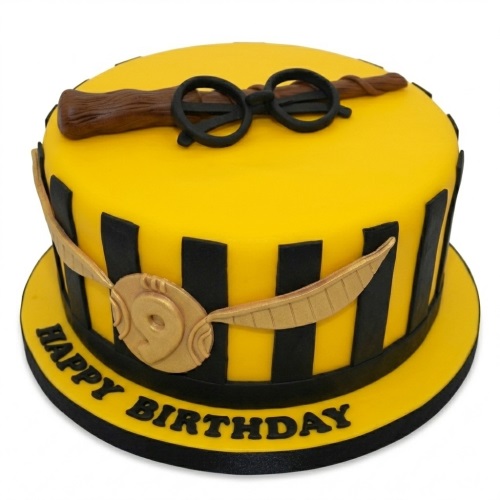 Round yellow and black Harry Potter theme birthday cake with edible wand, glasses, and golden snitch.
