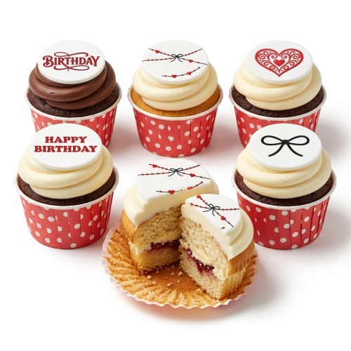 Assortment of birthday cupcakes with white frosting, red polka dot wrappers, and white fondant toppers featuring red hearts, black bows, and "Birthday" messages.