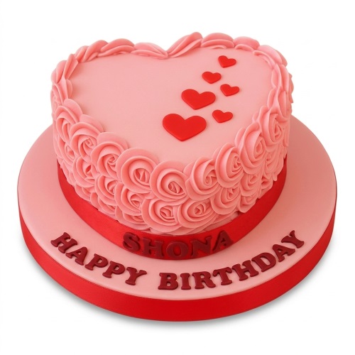 Pink heart-shaped birthday cake with piped rose details, red hearts, and a custom message area.