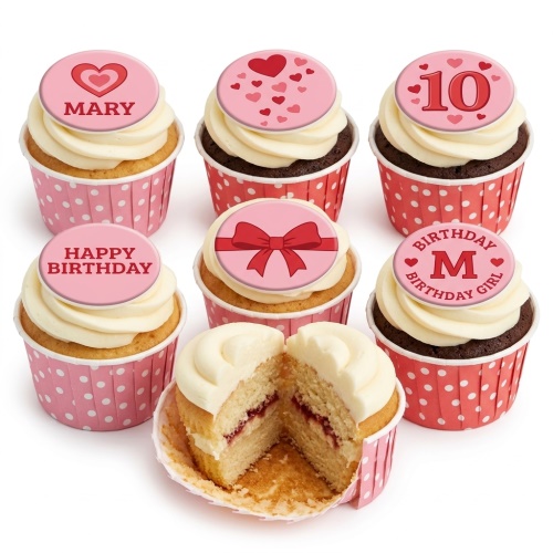 A selection of Girls Birthday Cupcakes with pink and red heart and bow toppers, some with custom age and initial, in polka dot cases.
