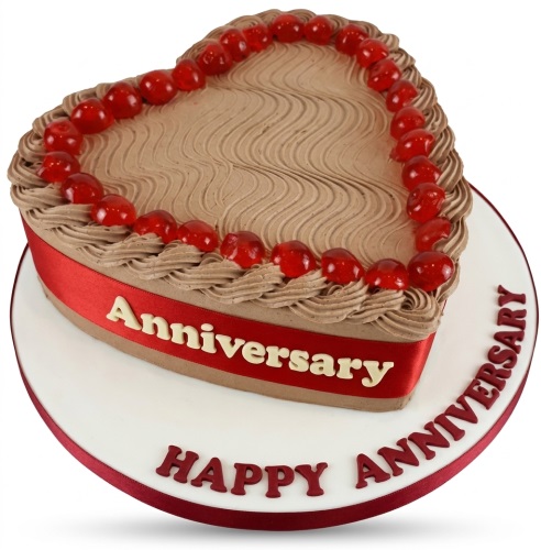 Heart-shaped anniversary cake with brown frosting, red ribbon, and red cherries.