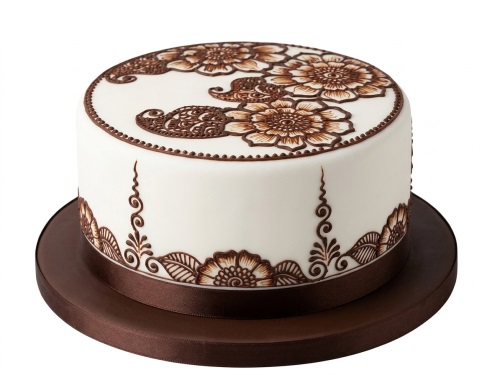 Round white cake with intricate brown henna-style floral patterns and a brown ribbon.