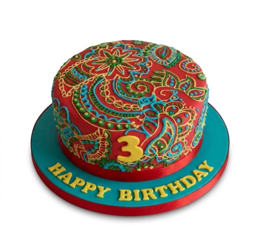 Red round cake with intricate turquoise, yellow, and green Indian-inspired piped patterns and a custom age topper.