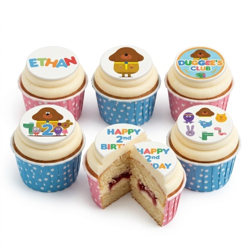 Hey Duggee themed cupcakes with white frosting, pink and blue polka dot cases, and edible toppers featuring Duggee, his friends, and a custom age message.