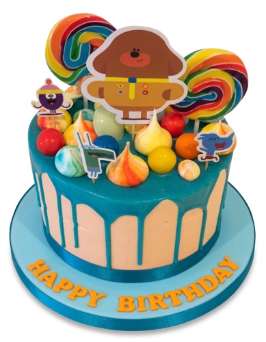 Round Hey Duggee birthday cake with teal drip, rainbow lollipops, and character toppers.