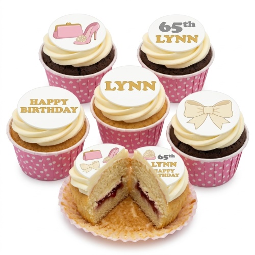 Birthday cupcakes with cream frosting, pink polka dot cases, and fashion toppers including a pink handbag, high heel, and bow.