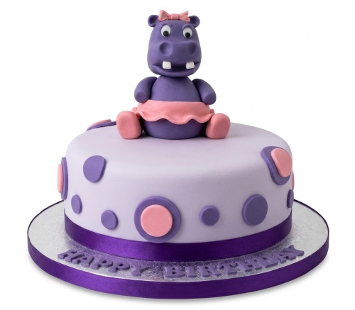 Round lavender birthday cake with a purple hippo figure, pink bow, and polka dot decorations.