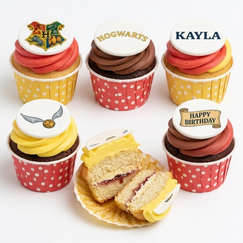 Selection of Harry Potter themed cupcakes with Hogwarts crest, Hogwarts text, Golden Snitch, and Happy Birthday toppers.