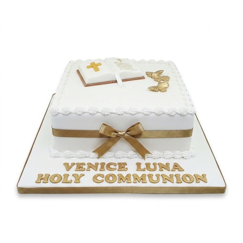 White square Holy Communion cake with gold bible, doves, and ribbon.