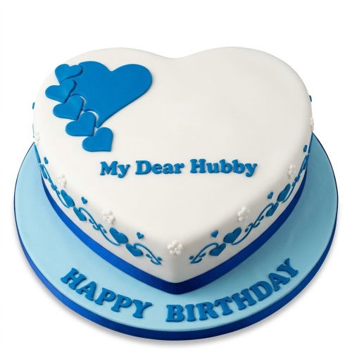 White heart-shaped birthday cake with blue hearts, blue swirls, and a personalised message.