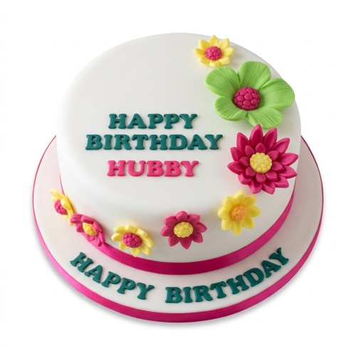 White two-tier cake with vibrant pink, yellow, and green fondant flowers and a custom message.
