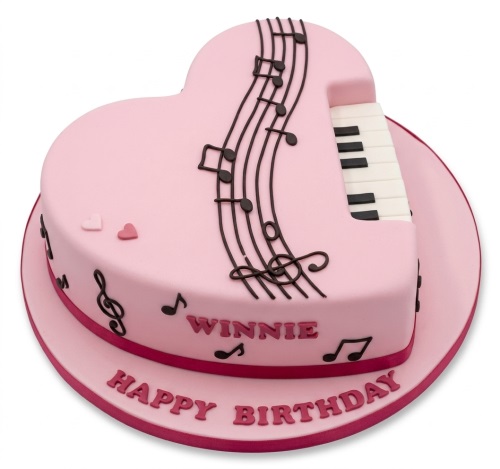 Pink heart-shaped cake with musical notes, piano keys, and space for a custom message.