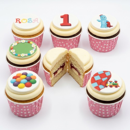 Assortment of kids birthday cupcakes with Igglepiggle, train, floral, and colourful dot toppers.