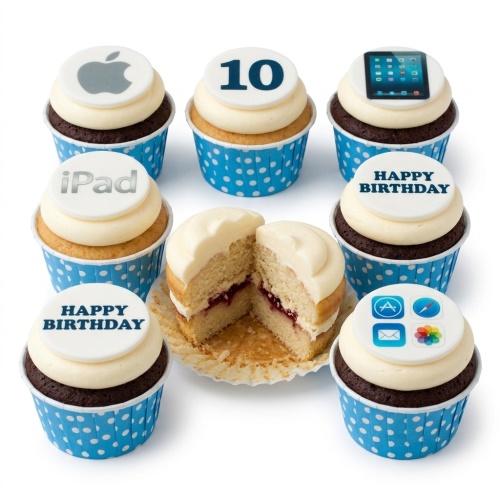 Assortment of Apple and iPad themed birthday cupcakes with custom age and 'Happy Birthday' toppers, in blue polka dot wrappers.