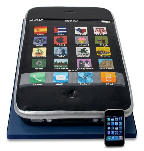 Black smartphone shaped cake with colourful edible app icons on a blue base.