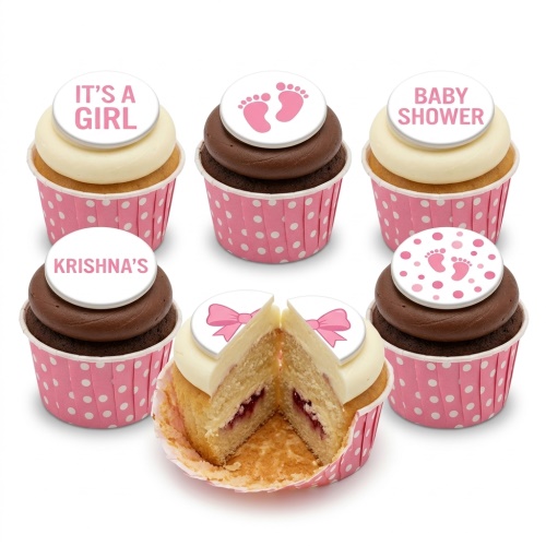 Pink and white baby shower cupcakes with 'It's a Girl' and baby footprint toppers.