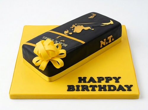 Black and gold whiskey bottle shaped birthday cake with a yellow bow and 'Happy Birthday' message.