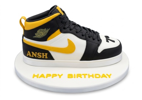 3D sculpted Jordans sneaker birthday cake in black, white, and yellow with custom name and message.