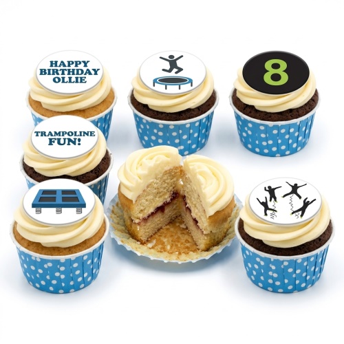 A selection of cupcakes with white icing and blue polka dot wrappers, featuring trampoline and jumping figures, and a custom age topper.