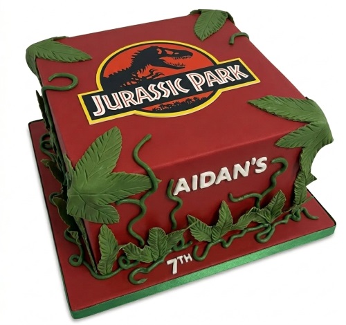 Red square Jurassic Park birthday cake with green vines, leaves, and custom name and age.