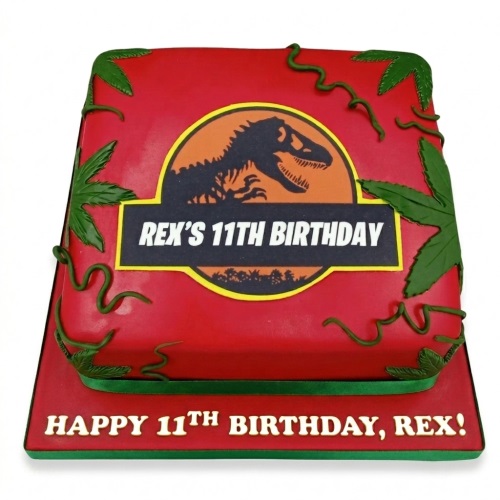 Red two-tier square dinosaur theme birthday cake with green leaves and a custom age logo.