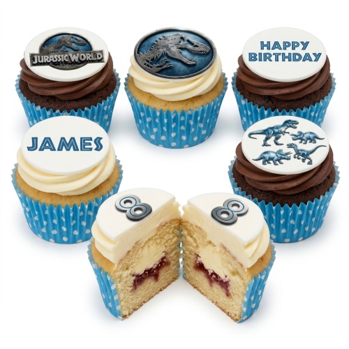 A selection of Jurassic World and dinosaur themed cupcakes with blue polka dot cases, some with custom name and age toppers.