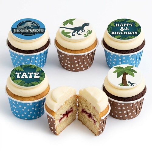 Six Jurassic World themed cupcakes with dinosaur, logo, palm tree, and leaf toppers.